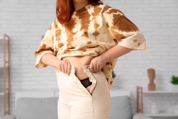 Image of woman trying to do her trousers up after pregnancy weight gain Berkshire